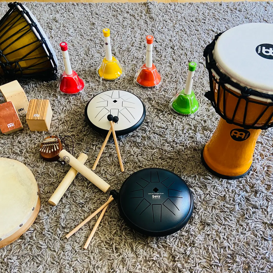 Djembés, tambourins, cloches musicales colorées, claves et tambours à langue posés au sol